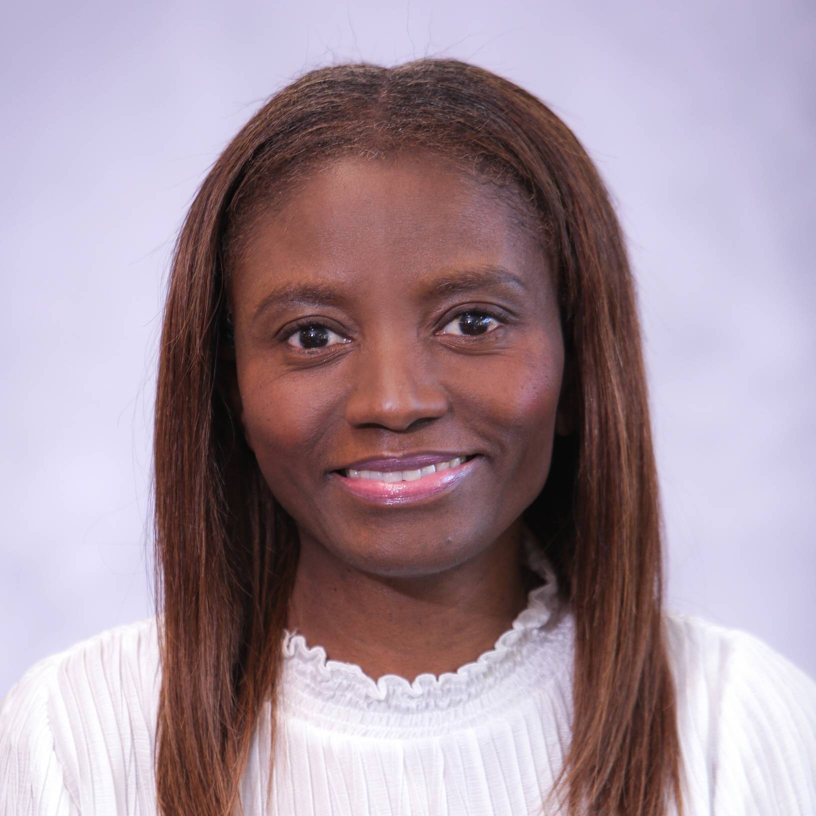 A headshot of Roselle Caruth. A smiling, Black woman with a white top with a light blue background.