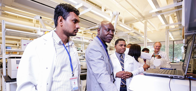 A group of researchers look at a laptop screen