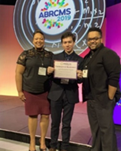 three students hold an award at the Annual Biomedical Research Conference for Minority Students