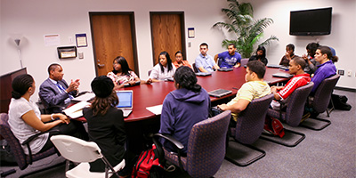 a group of students sit around an oval table