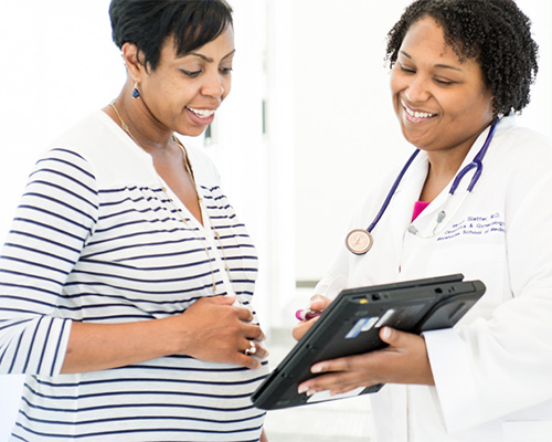 a pregnant woman looks at a doctor's tablet