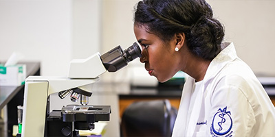 a woman looking into a microscope