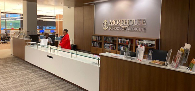 the library circulation desk with smiling staff standing behind it