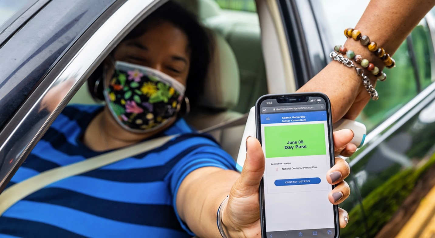 Woman holding a phone showing a National Center for Primary Care guest pass.