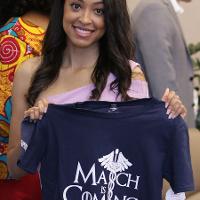 a woman holds a shirt that says March is Coming