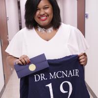 a woman holds a shirt reading Dr. McNair 19