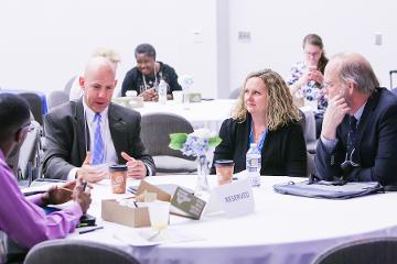 a group of people sit around a table discussing research