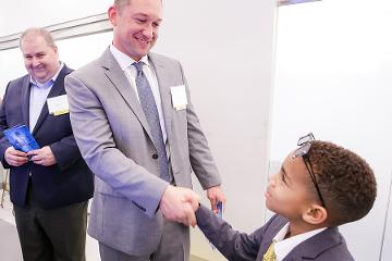 a man shakes the hand of a young boy