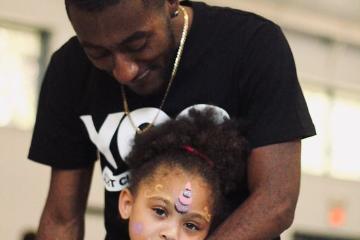 a man wraps his arm around a young girl with facepaint