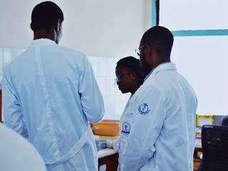 a group of people in whitecoats work with lab equipment