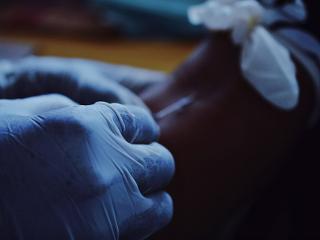 a close-up of injecting a needle into an arm