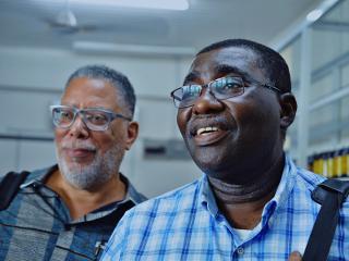 two men look on past the camera