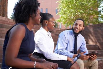 a group of people smile while sitting on brick stairs