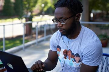 a man works on a laptop while wearing headphones