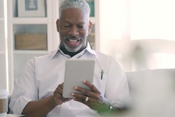 a man smiles while holding a tablet
