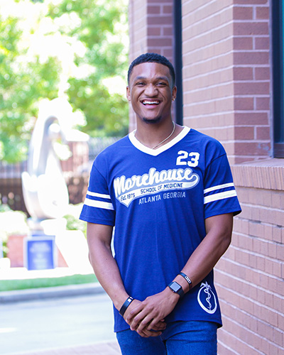 a man wearing a Mohrouse Schoolf of Medicine jersey smiles at the camera