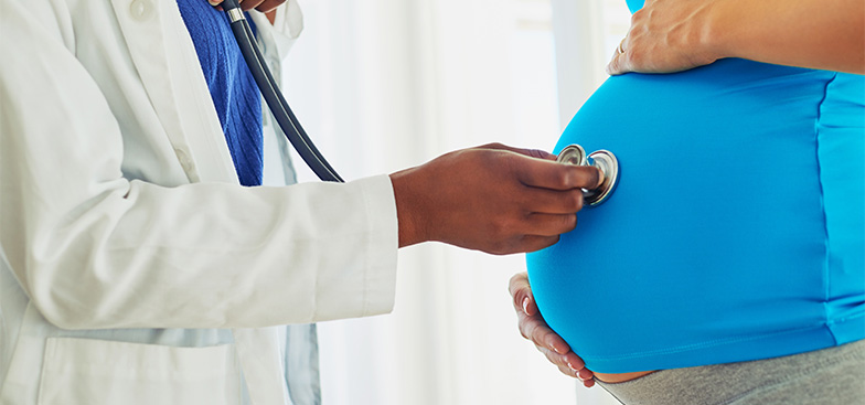 a doctor holds a stethoscope to a pregnant woman's stomach