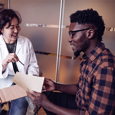 a man holds a paper while a doctor smiles next to him